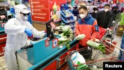 Un trabajador con un traje protector atiende a clientes en un supermercado tras el brote de coronavirus en Wuhan, provincia de Hubei province, China, el 12 de febrero de 2020.