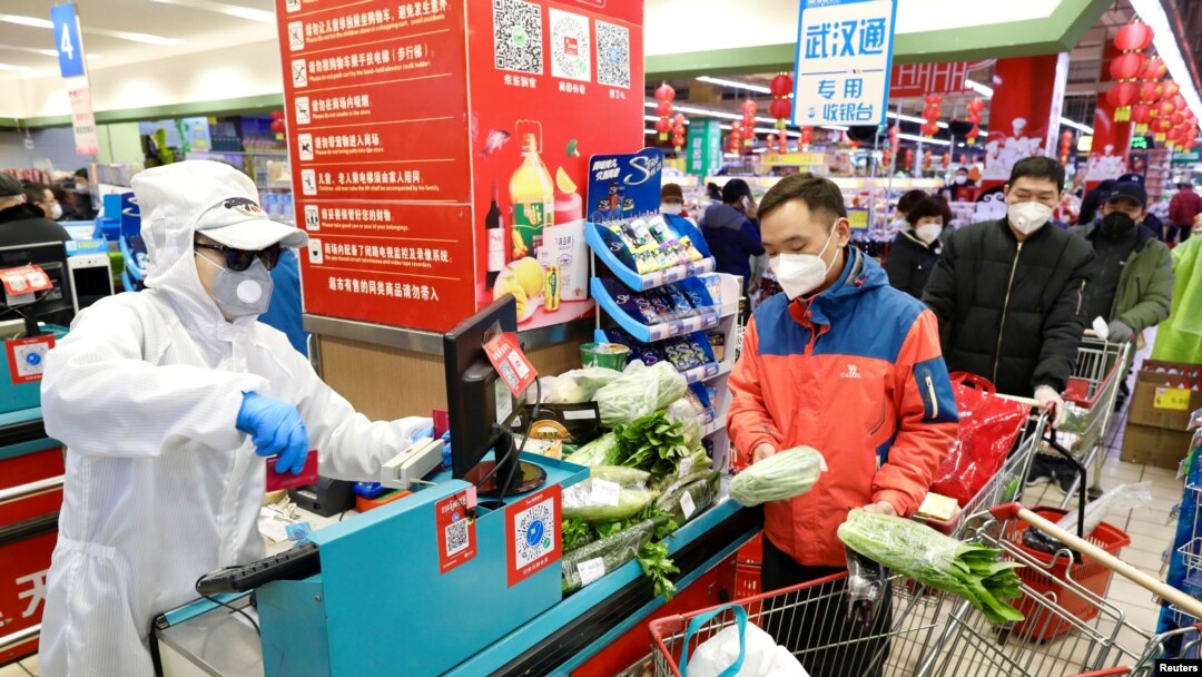 Prodavac u zaštitnoj odeći uslužuje kupce na kasi supermarketa, u Vuhanu, pokrajina Hubej, Kina, 12. februara 2020. (PHOTO: China Daily via REUTERS)