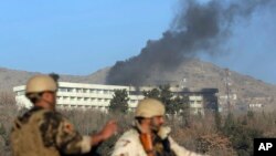 Afghan security personnel stand guard as black smoke rises from the Intercontinental Hotel, Jan. 21, 2018, after an attack in Kabul, Afghanistan. Gunmen stormed the hotel and set off a 12-hour gun battle with security forces that continued into Sunday morning, as frantic guests tried to escape from fourth- and fifth-floor windows.