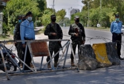 Pakistan paramilitary soldiers and a police officers stand guard at a checkpoint of a restricted area to help to contain the spread of new coronavirus, in Islamabad, Pakistan, Saturday, June 13, 2020. Capital administration sealed few areas of…