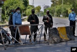 Pakistan paramilitary soldiers and a police officers stand guard at a checkpoint of a restricted area to help to contain the spread of new coronavirus, in Islamabad, Pakistan, Saturday, June 13, 2020. Capital administration sealed few areas of…
