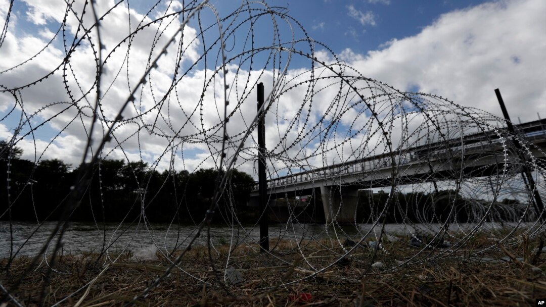 FILE - Razor wire recently placed by the U.S.military along the banks of the Rio Grande frames the McAllen-Hidalgo International Bridge at the U.S.-Mexico border, Nov. 3, 2018, in McAllen, Texas.