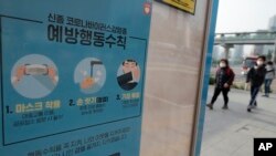 Para pejalan kaki mengenakan masker mendekati halte bus yang ditempeli poster peringatan bahaya pandemi corona di Seoul, Korea Selatan, 25 Mei 2020.