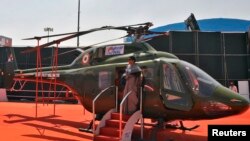 Seorang perempuan berpose di depan helikopter milik Angkatan Udara India (IAF) di bandara militer Yelahanka, Bengaluru (Foto: dok).