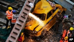 Rescue workers cut through parts of a partially collapsed overpass in Kolkata, India, March 31, 2016. 