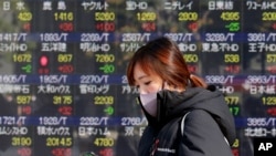 A woman walks by an electronic stock board of a securities firm in Tokyo, Dec. 16, 2020. 