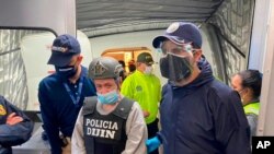 In this photo released by the Colombian Migration Press Office, ex-paramilitary commander Hernan Giraldo Serna, center, is escorted upon arrival at the El Dorado airport after being deported from the U.S. to Bogota, Colombia, Jan. 25, 2021.