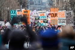 Demonstrators wave signs during the People's March in Washington, Jan. 18, 2025.