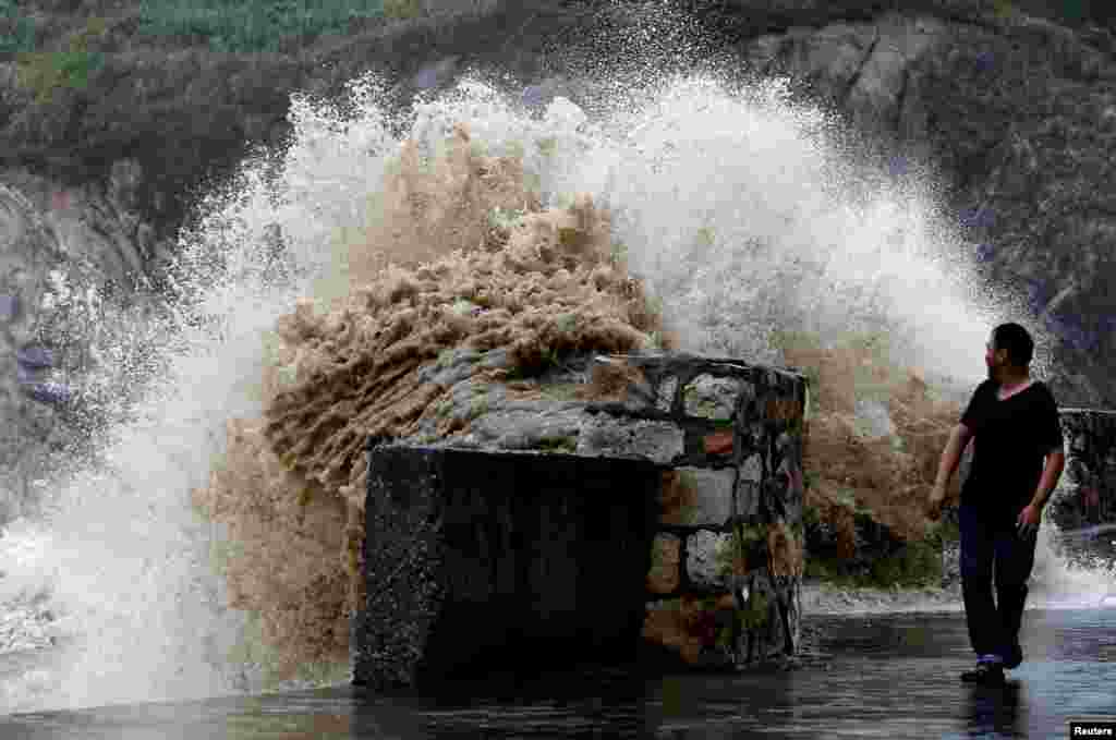 A man looks back at a surging wave as Typhoon Trami approaches China, in Wenling, Zhejiang province, Aug. 21, 2013.