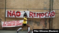 Um jogador de futebol chuta uma bola durante o torneio organizado pela Copa Popular, com participação de 10 favelas, para protestar contra remoções forçadas. 15 de Junho de 2013.