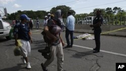 Un migrant tombé d'un véhicule est décédé alors que d'autres migrants marchent dans la banlieue de Tapachula, au Mexique, le 22 octobre 2018. 