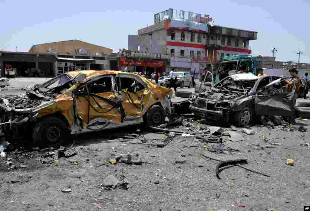 Civilians and security forces inspect the site of a suicide bomb attack in Tuz Khormato, Iraq, June 9, 2014.