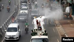 Para petugas Palang Merah Indonesia mengenakan baju hazmat menyemprotkan disinfektan untuk mencegah penularan virus corona (COVID-19), Jakarta, 28 Maret 2020. (Foto: Reuters)