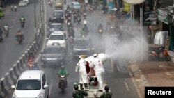 Para petugas Palang Merah Indonesia mengenakan baju hazmat menyemprotkan disinfektan untuk mencegah penularan virus corona (COVID-19), Jakarta, 28 Maret 2020. (Foto: Reuters)