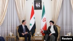 Presiden Suriah Bashar Al Assad (kiri) dan Presiden Iran Ebrahim Raisi dalam pertemuan di Teheran, Minggu (8/5). 