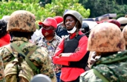 FILE - Ugandan opposition presidential candidate Robert Kyagulanyi, also known as Bobi Wine, is escorted by policemen during his arrest in Kalangala in central Uganda, Dec. 30, 2020.