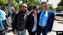 El fotógrafo colombiano Leonardo Muñoz (I) y la periodista colombiana Mauren Barriga Vargas (C) aparecen en la foto junto al encargado de negocios de Colombia en Venezuela, Germán Castaneda, luego de ser liberado de la detención por las autoridades venezolanas, en Caracas.