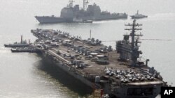 Kapal induk pembawa pesawat tempur, USS Ronald Reagan berlabuh saat kapal Aegis Amerika berlayar melewati setibanya di Pelabuhan Busan untuk latihan militer gabungan di Busan, Korea Selatan. Amerika dan Korea Selatan memulai latihan angkatan laut bersama pada 11 November 2017. 