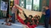 Vendors unfurl a banner from 1969 depicting former Chinese leader Mao Zedong as he "inspects the great army of the Cultural Revolution" and the slogan "Navigating the seas depends on the helmsman" at a curio market in Beijing, China, May 16, 2016. 