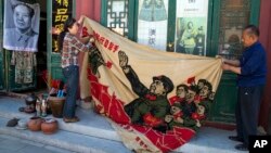 Pedagang kaki lima membentangkan banner bergambar pemimpin China Mao Zedong di Beijing, China, Senin (16/5) pada peringatan HUT ke-50 Revolusi Kebudayaan China.