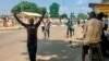 TOPSHOT - People are obliged to walk with their hands upon their heads as they pass security checkpoints, held by security forces wearing civil clothes and holding machetes and sticks to control the crowd, at Obalende Market, Lagos, Nigeria, on…