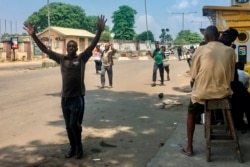 People are required to walk with their hands up as they pass security checkpoints, held by security forces holding machetes and sticks to control the crowd, at Obalende Market, Lagos, Nigeria, Oct. 23, 2020.