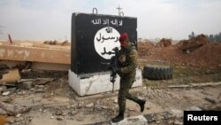 FILE - An Iraqi soldier walks next to a wall painted with the black flag commonly used by Islamic State militants, north of Mosul, Iraq, Jan. 21, 2017. 