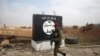 FILE - An Iraqi soldier walks next to a wall painted with the black flag commonly used by Islamic State militants, north of Mosul, Iraq, Jan. 21, 2017. 