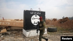 FILE - An Iraqi soldier walks next to a wall painted with the black flag commonly used by Islamic State militants, north of Mosul, Iraq, Jan. 21, 2017.