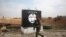 FILE - An Iraqi soldier walks next to a wall painted with the black flag commonly used by Islamic State militants, north of Mosul, Iraq, Jan. 21, 2017. 