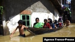 A family evacuates from their flooded home following heavy rain in Bandung, Indonesia.