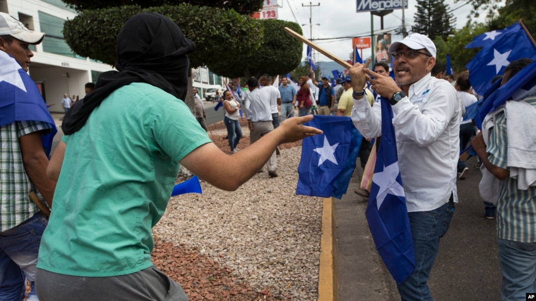 AUn miembro del Partido Nacional (derecha), se enfrenta a un manifestante antigubernamental durante una reunión para mostrar su apoyo a la reelección del presidente Juan Orlando, en Tegucigalpa, Honduras. Dic. 7, 2017.