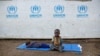 (FILE) In this June 9, 2017, file photo, a South Sudanese refugee boy sits on a mat outside a communal tent while his brother sleeps, at the Imvepi reception center in northern Uganda.