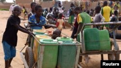Displaced children that fled from their villages in northern Burkina Faso, following attacks by assailants, push carts loaded with water at a school in Ouagadougou, Burkina Faso, June 15, 2019. 
