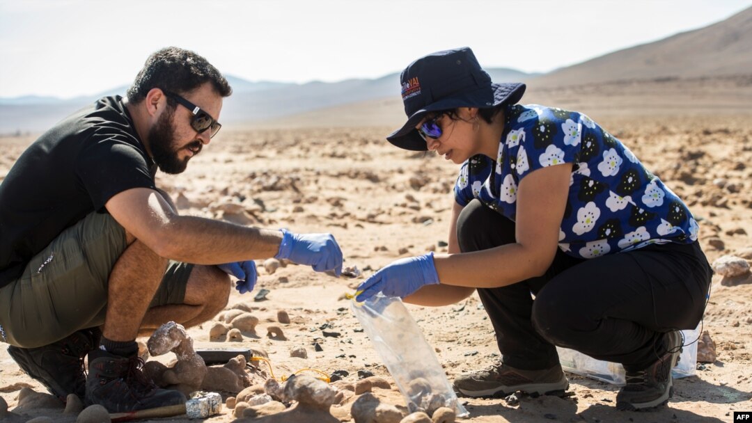 Ahli biologi Chili Cristiana Dorador dan Jonathan Garcia mencari sampel batuan untuk menganalisisnya di Yungay, Gurun Atacama, sekitar 80 kilometer selatan Antofagasta, Chili pada 7 Maret 2017, sebagai ilustrasi. (Foto: AFP)