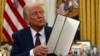 FILE - President Donald Trump holds up a signed executive order in the Oval Office of the White House, in Washington, Jan. 23, 2025.