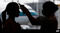 A passenger arriving from Busan, South Korea, receives a temperature check for MERS (Middle East Respiratory Syndrome) as she arrives at Hong Kong Airport, June 5, 2015.