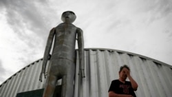 FILE - In this July 22, 2019 file photo, Linda Looney wipes her face outside of the Alien Research Center, a gift shop on the Extraterrestrial Highway, in Crystal Springs, Nevada.