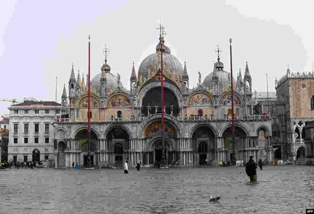 People walk in the flooded St. Mark Square in Venice, Italy.