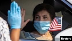 A U.S. immigration officer administers the oath as a swearing-in of newly naturalized United States citizens takes place in an empty parking lot during the outbreak of the coronavirus disease (COVID-19) in Santa Ana, California, July 29, 2020. 