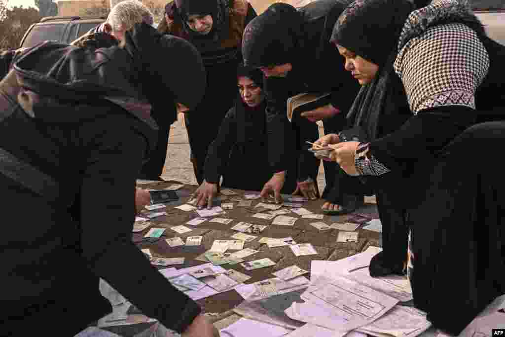 People search documents to find any information on their missing relatives at the Mazzeh military airport, outside Damascus, Syria.