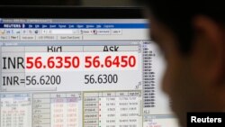 A currency trader works in front of a screen showing the value of the Indian rupee against the U.S. dollar on the floor of a trading firm in Mumbai, May 31, 2013. 