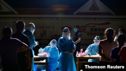 Medical workers attend to people lining up for nucleic acid testing at a residential compound in Ruili, Sep. 17, 2020.