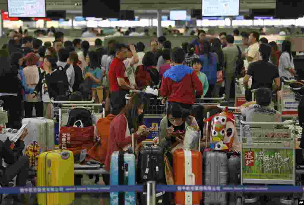 Passengers whose travel plans were affected by Typhoon Usagi wait at airline counters at Hong Kong's international airport, Sept. 23, 2013.