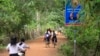 Children ride their bicycles past a sign bearing the Cambodian People's Party logo and the faces of Prime Minister Hun Sen and National Assembly President Heng Samrin in Banteay Meas village, Taches commune, Kampong Chhnang province, Nov. 8, 2017. 