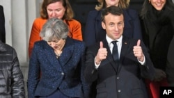 Prime Minister Theresa May (L) and French President Emmanuel Macron prepare for a group photo during UK-France summit talks at the Royal Military Academy Sandhurst, in Camberley, England, Jan. 18, 2018. 