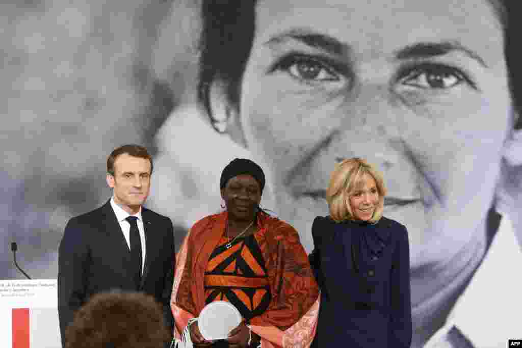 Cameroonian activist Aissa Doumara Ngatansou (C) poses for a photo with French President Emmanuel Macron (L) and his wife Brigitte Macron (R) after she received the Simone Veil prize, at the Elysee Palace, in Paris, on March 8, 2019 during International Women&#39;s Day.