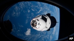 FILE - In this April 24, 2021, photo made available by NASA, the SpaceX Crew Dragon capsule approaches the International Space Station. Space junk is threatening the astronauts aboard the International Space Station and forcing them to seek shelter in thei