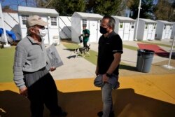 Hope of the Valley CEO Ken Craft, right, talks to Ted Beauregard, who lives in the village, outside of a row of tiny homes for the homeless, February 25, 2021. (AP Photo/Marcio Jose Sanchez)