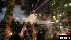 FILE - A firework explodes near police officers during a rally of opposition parties' supporters, who protest against the new government's decision to suspend the European Union accession talks and refuse budgetary grants until 2028, in Tbilisi, Georgia November 30, 2024.